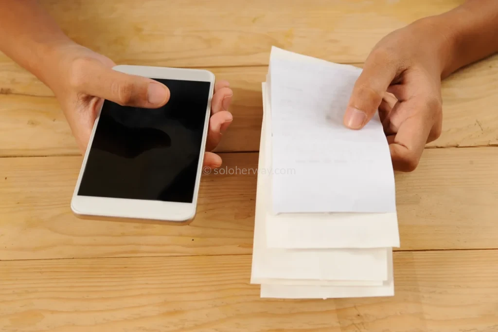 How To Handle Medical Bills and Insurance Abroad: What Every Traveler Needs To Know 3 Checking Bills on Smartphone While Reviewing Documents 1