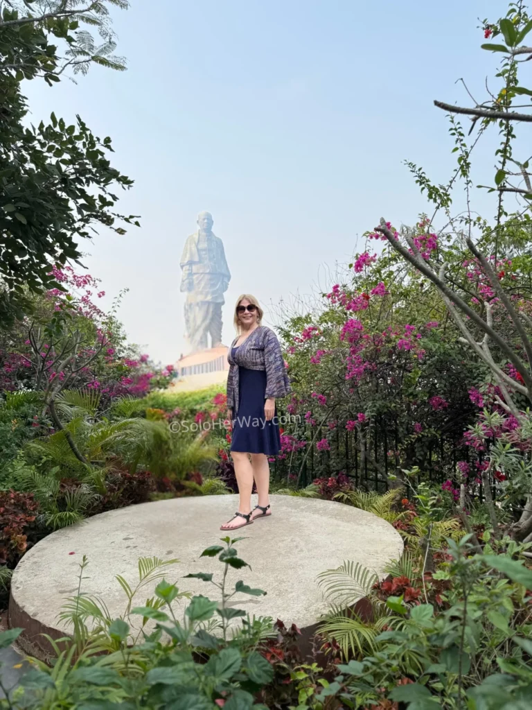 Beautiful garden viewpoint with colorful flowers and a scenic view of the Statue of Unity in the background during daytime.