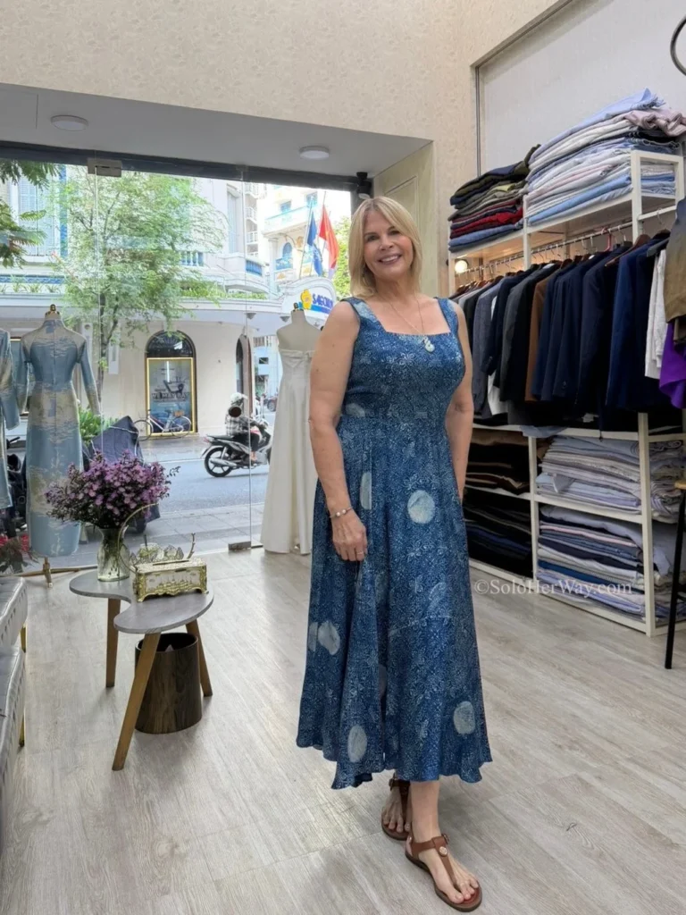 Getting Clothes Made in Hoi An & Ho Chi Minh City: What I Wish I’d Known 7 Traveler wearing a custom-made blue dress inside a tailoring boutique, highlighting the value of investing in quality bespoke clothing.