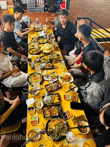 Ho Chi Minh City locals enjoy a lively group meal with Vietnamese dishes, drinks, and friends gathered around a restaurant table.