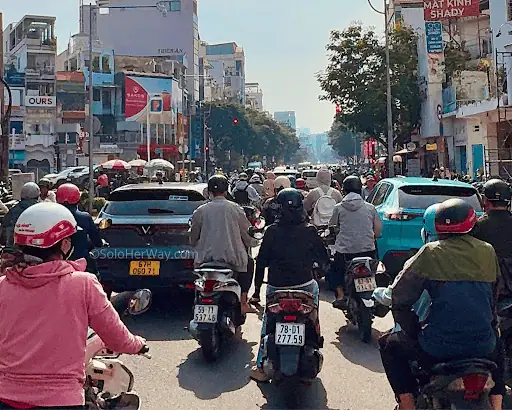 Ho Chi Minh City traffic with motorbikes, cars, local shops, and busy street life in the heart of Vietnam's largest city.
