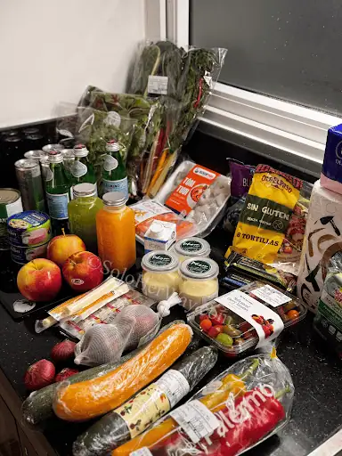 Ho Chi Minh City grocery haul with fresh produce, drinks, snacks, and packaged foods arranged on a kitchen counter in Vietnam.